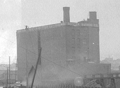 Vintage black and white photograph of a large industrial building with 'Boston Sutton Co.' branding